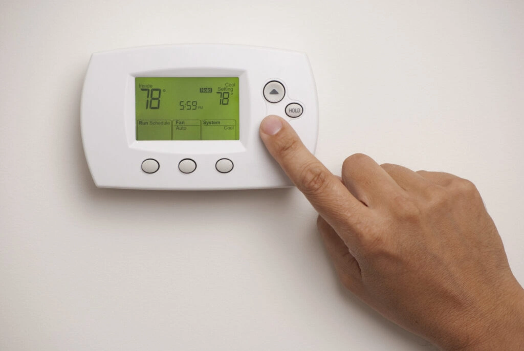 Homeowner adjusting thermostat settings, relevant to understanding what is emergency heat on a thermostat
