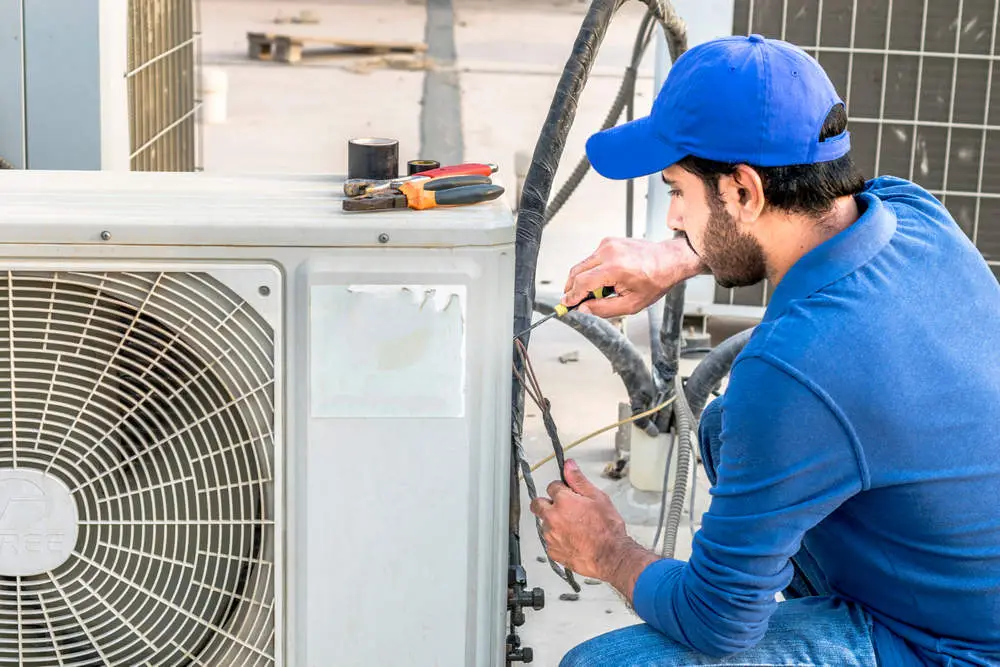 Do you tip AC repair guy working on outdoor air conditioner unit fixing wiring and components